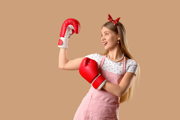 Young pin-up woman in boxing gloves on beige background. Women's History Month