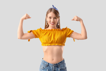 Young pin-up woman showing muscles on white background. Women's History Month