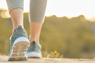Person walking on a scenic path during golden hour in comfortable athletic shoes with natural surroundings