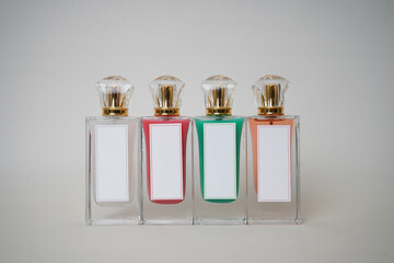 A row of four stylish perfume bottles with blank white labels and gold caps in varied pastel colors. Perfect for branding, fragrance product mockups, or luxury beauty content creation.

