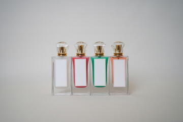 A row of four stylish perfume bottles with blank white labels and gold caps in varied pastel colors. Perfect for branding, fragrance product mockups, or luxury beauty content creation.

