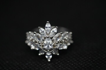 Close-up of a luxurious silver ring with marquise-cut stones arranged in a floral design, set against a textured black background. Perfect for jewelry, fashion, luxury, and bridal themes.