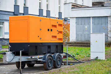 Industrial diesel generator connected to power distribution box. Backup generator on trailer...