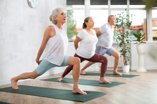 Active elderly women adn man practicing various yoga positions during training