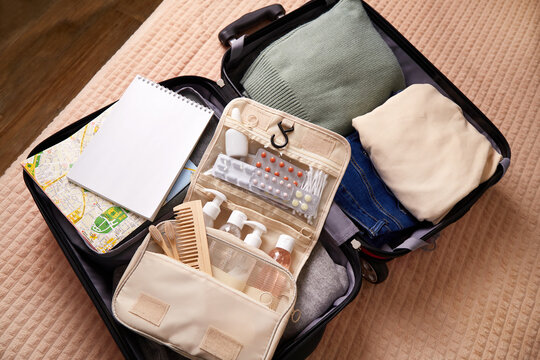Open suitcase packed with clothing, toiletries, and travel essentials ready for a trip.  - Powered by Adobe