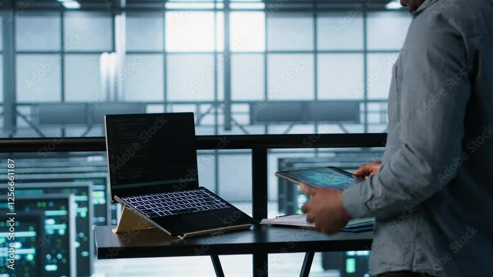 Poster technician in data center using ai on laptop and tablet, developing disaster recovery plans. server 