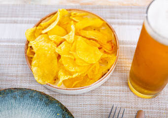 Plate with crunchy potato chips served with glass of beer
