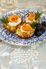 Crispy hashbrown potato nest with goat cheese and salmon lox with black berries