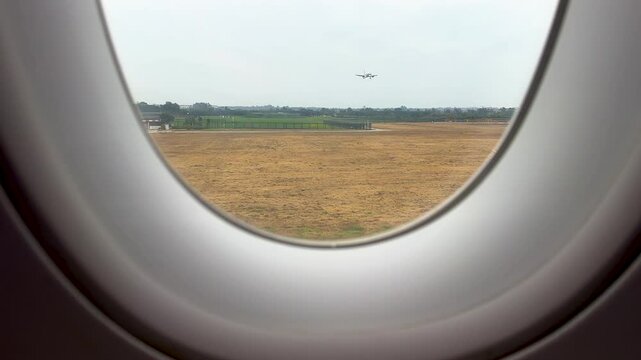 View of a landing airplane from the porthole of an aircraft in Chengdu Shuangliu International Airport, Chengdu, Sichuan, China.