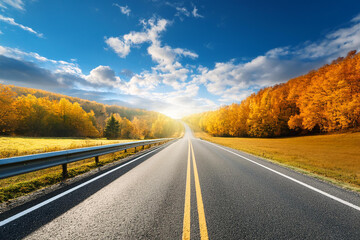 Fototapeta premium Beautiful rural road in autumn season forest. Royalty high-quality free best stock of Scenic autumn Winding road with colorful foliage, amazing landscape nature, fall color trees woods