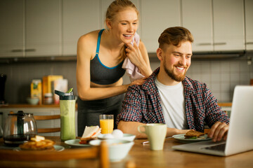 Young couple having breakfast together in the morning and using a laptop