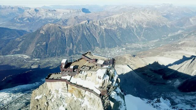 Breathtaking view from the highest point of Aiguille du Midi with the glass skywalk, overlooking the lower cable car station, Chamonix valley, and the stunning peaks of the French Alps.