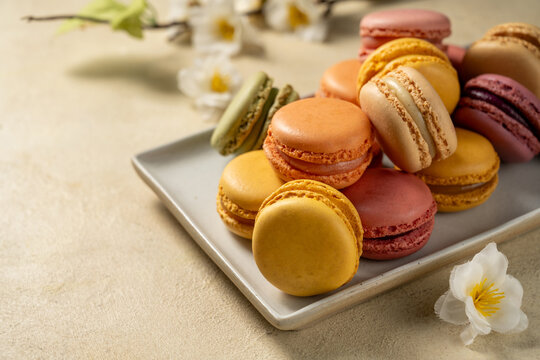 Macarons cookies in a plate, french macarons. Spring flowers on background
