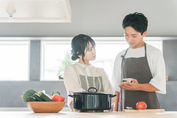 料理をしながらイライラするヒステリーな主婦の女性と男性（モラハラ・レシピアプリ）
