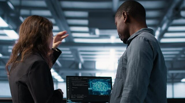 Software developers in data center using laptop, employing AI machine learning models. Workers using notebook to fulfill artificial intelligence infrastructure needs, allocating resources, camera A