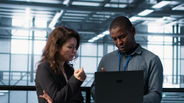 Engineers using laptop in data center, managing server virtualization, running scripts. IT specialists using programming language on notebook in server hub, finetuning network protocols, camera A