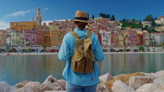 Beautiful woman walking at background colorful houses in Menton, France. Cote d'Azur, France
