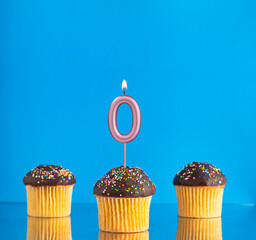 Three birthday cupcakes with number 0 candle - Blue background.