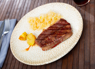 Service plate containing roast beef meat, potato and pickled cabbage with necessary table laying