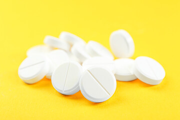 Pile of antibiotic pills on yellow background, closeup