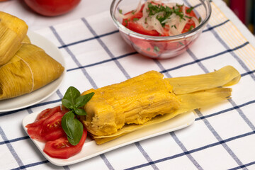 Humita en hojas, plato típico Chileno en Verano, junto a ensalada de tomate decorada con unas...