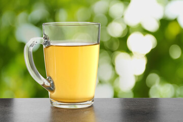Green tea in cup on grey textured table outdoors. Space for text