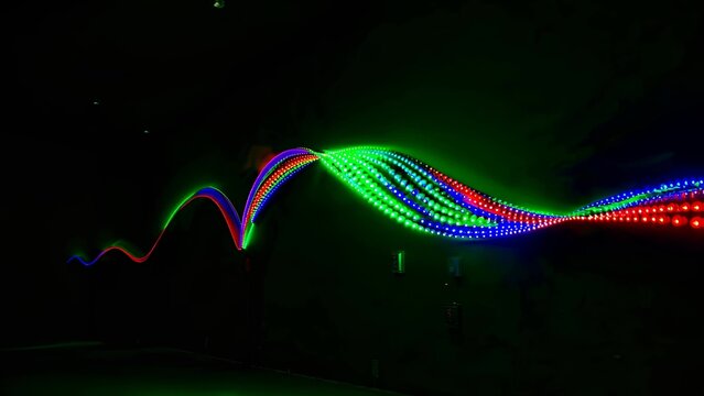 Dynamic display of multicolored led light waves forming vibrant patterns on a dark background, showcasing the beauty of modern technology and artistic design in an abstract form