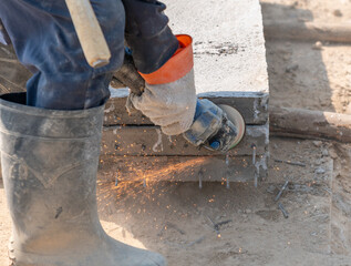 Close up worker is using grinder for cutting reinforcing steel.