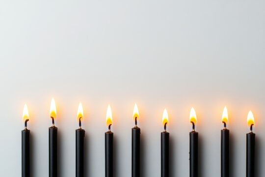 Eight black candles burn brightly on white. Perfect for remembrance, loss, or somber events.