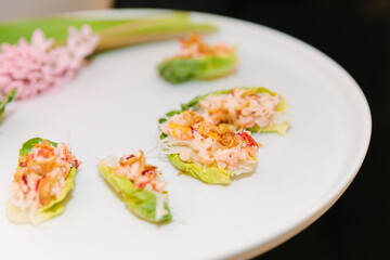 Crisp lettuce cups filled with fresh seafood, presented elegantly at a gourmet dining event in the evening