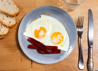 Delicious fried eggs with chistorra sausage served on platter for breakfast