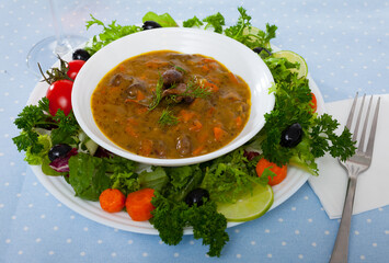 Top view of tasty goulash from chicken hearts with lettuce at plate, fresh vegetables