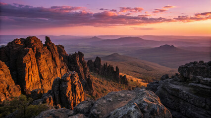 Obraz premium Sunset over rugged mountain peaks with dramatic rock formations and vast landscape