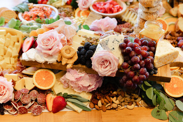 Colorful charcuterie board with assorted cheeses, fruits, and flowers for a gathering