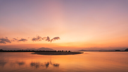 Fototapeta premium Orange sunset sky clouds over sea in the evening with yellow sunlight, Horizon sea sky landscape background and sun down in golden hour summer season, Dusk