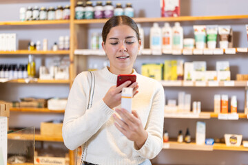 Girl get acquainted with dietary supplement, scan QR code, take reading label using phone camera in...