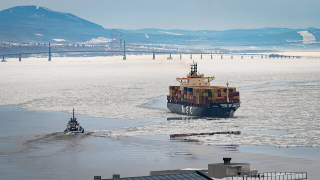 An MSC cargo vessel heads up the St. Lawrence River from Quebec City, Canada in the winter accompanied by a small tugboat on Feb. 15, 2023.  Import Tariffs. Trade Sanctions.