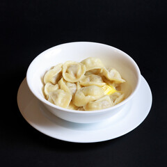 Dumplings with butter on a white plate, shot on a black background
