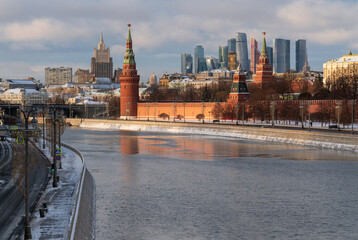 Obraz premium Vodovzvodnaya, Blagoveshchenskaya and Borovitskaya towers on the Kremlin embankment of the Moskva River and the Moscow City Business Center in the background on a sunny winter day, Moscow, Russia