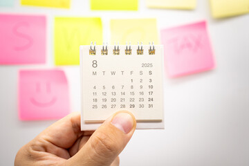 Hand holding mini calendar for AUGUST 2025 background. Calendar concept with 2025 AUG calendar....