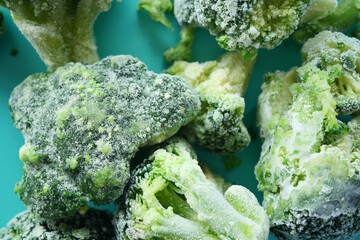 Frozen broccoli pieces on a blue surface ready for cooking