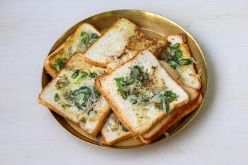 Delicious bread fried with chilies, onions, eggs, and ghee (clarified butter), served on a brass plate on a light wooden surface. This is a very tasty and healthy homemade breakfast.