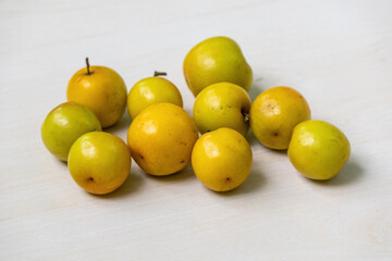 Fresh, ripe plum fruits rest on a light wooden surface. Locally known as Boroi or Kul in Bangladesh, this fruit is also called Indian jujube, Chinese date, or Chinee apple.