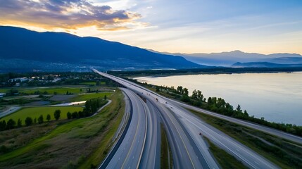 Aerial view of winding highway near mountains and a serene river at sunset : Generative AI