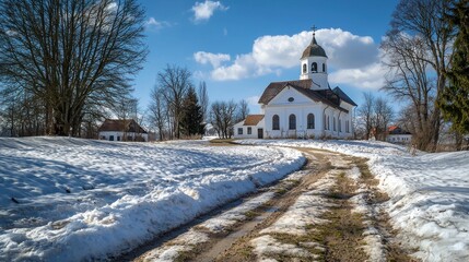 A tranquil scene featuring a white church surrounded by snow. The clear blue sky adds serenity to the picturesque landscape, ideal for winter-themed projects.