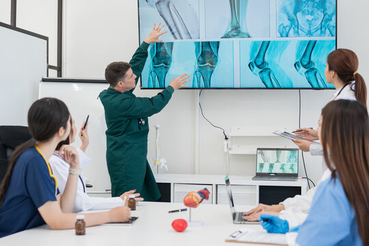  Multi-ethnic healthcare team meets about surgery at pharmaceutical company hospital - Powered by Adobe