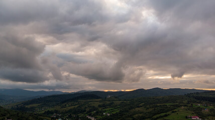 Majestic Mountains, Dense Forest, And Dramatic Clouds Illuminated By A Stunning Sunset. Aerial View Capturing The Breathtaking Beauty Of Nature From A Bird’s-Eye Perspective.
