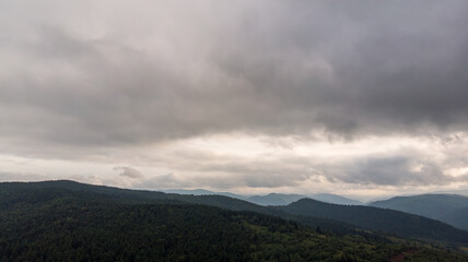 Magnificent Aerial View Of Mountains And Dense Forests Under Dark Clouds, With Raindrops Falling, Creating A Dramatic And Serene Atmosphere In A Remote Natural Landscape.