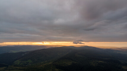 Aerial Flight Over Majestic Mountains And Dense Forests, Shrouded In Misty Clouds With Rainfall, Creating A Dramatic And Serene Landscape Of Untouched Wilderness.