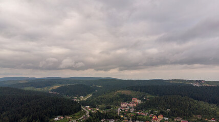 Fototapeta premium Magnificent Aerial View Of Mountains And Dense Forests Under Dark Clouds, With Raindrops Falling, Creating A Dramatic And Serene Atmosphere In A Remote Natural Landscape. 